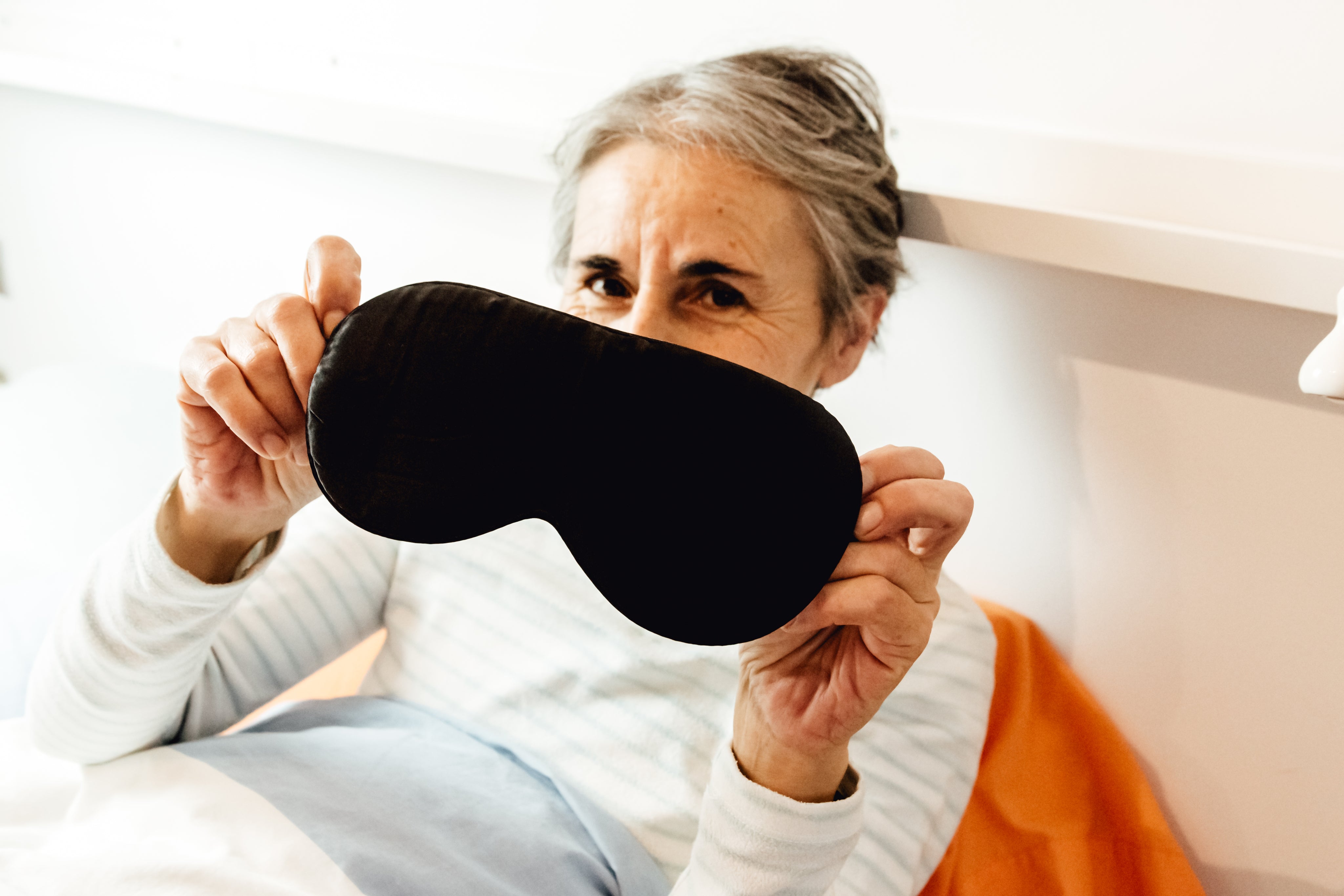 files/person-in-bed-holds-their-eye-mask-for-the-camera.jpg